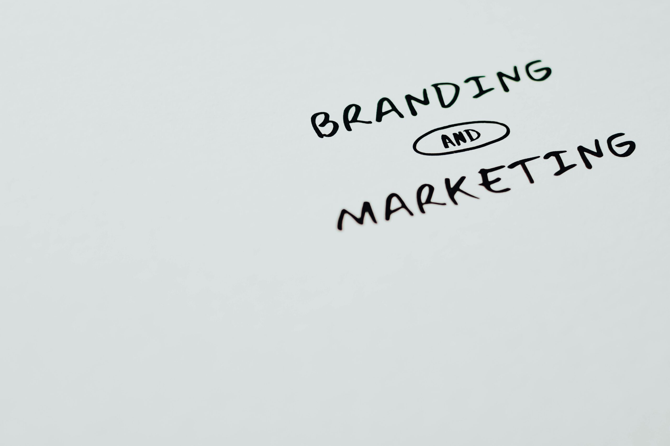 The words “Branding and Marketing” handwritten on a white surface.