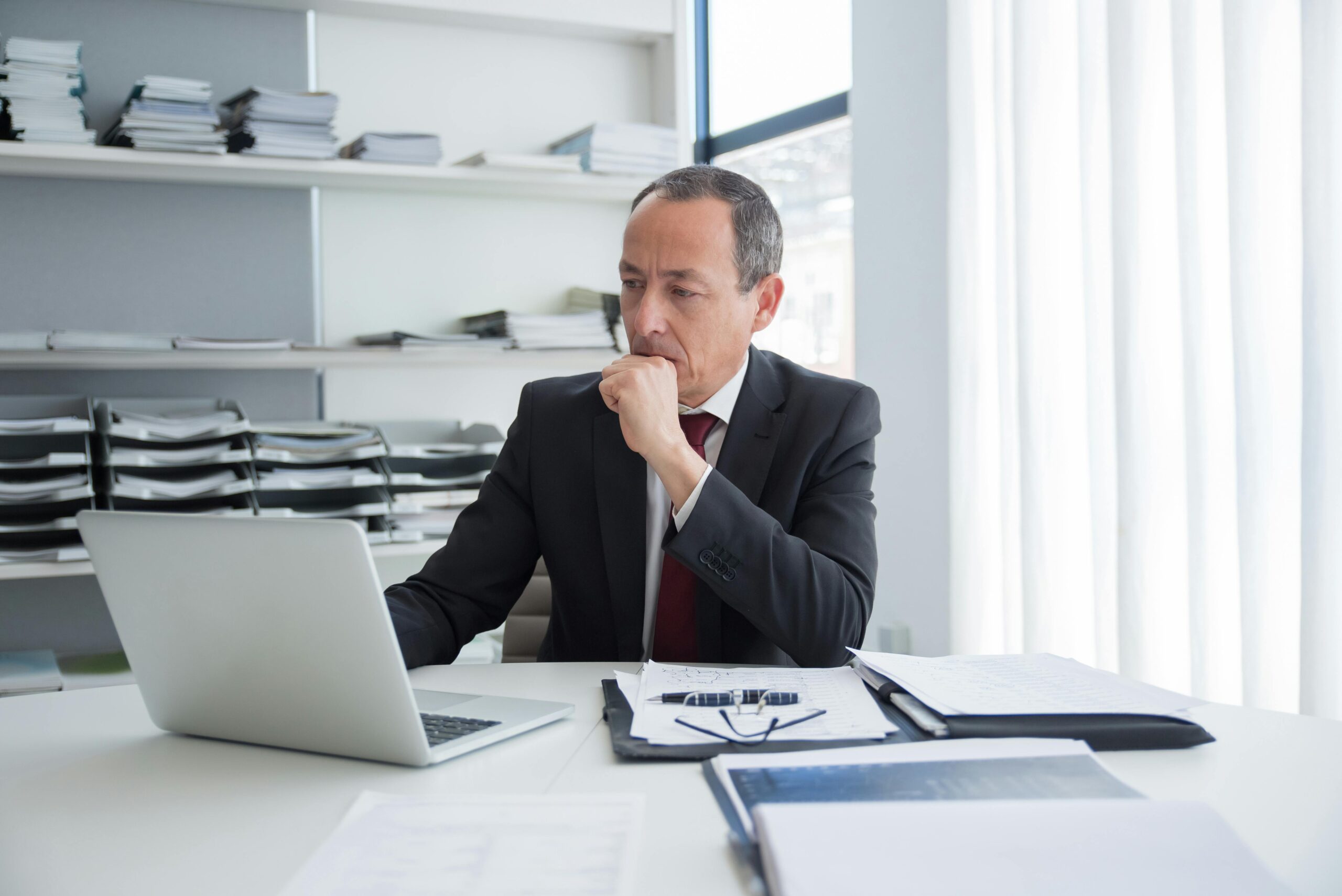 Man in White Dress Shirt Sitting on Black Rolling Chair While Facing Black Computer Set and Smiling